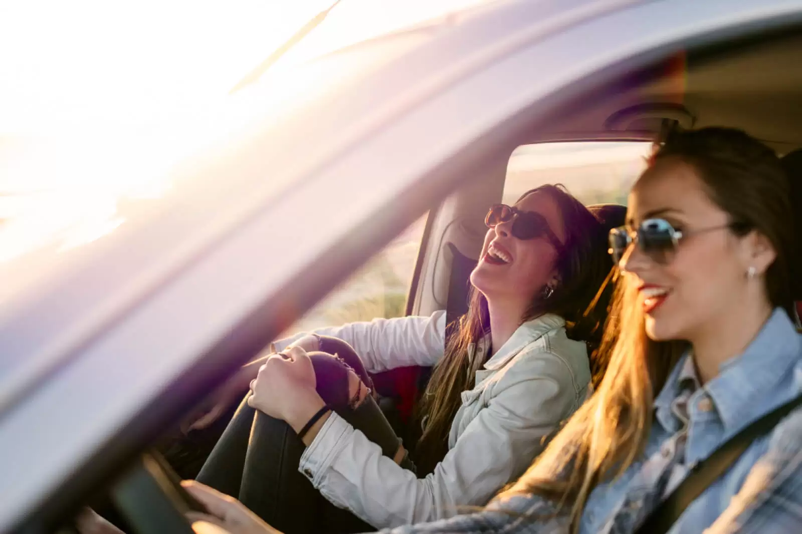 Dos chicas sonriendo dentro de un coche de renting en oferta